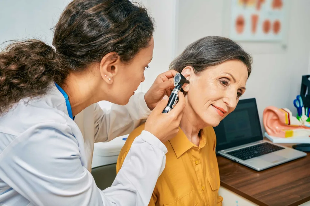 audiologist examines her patient's hears during an annual hearing exam