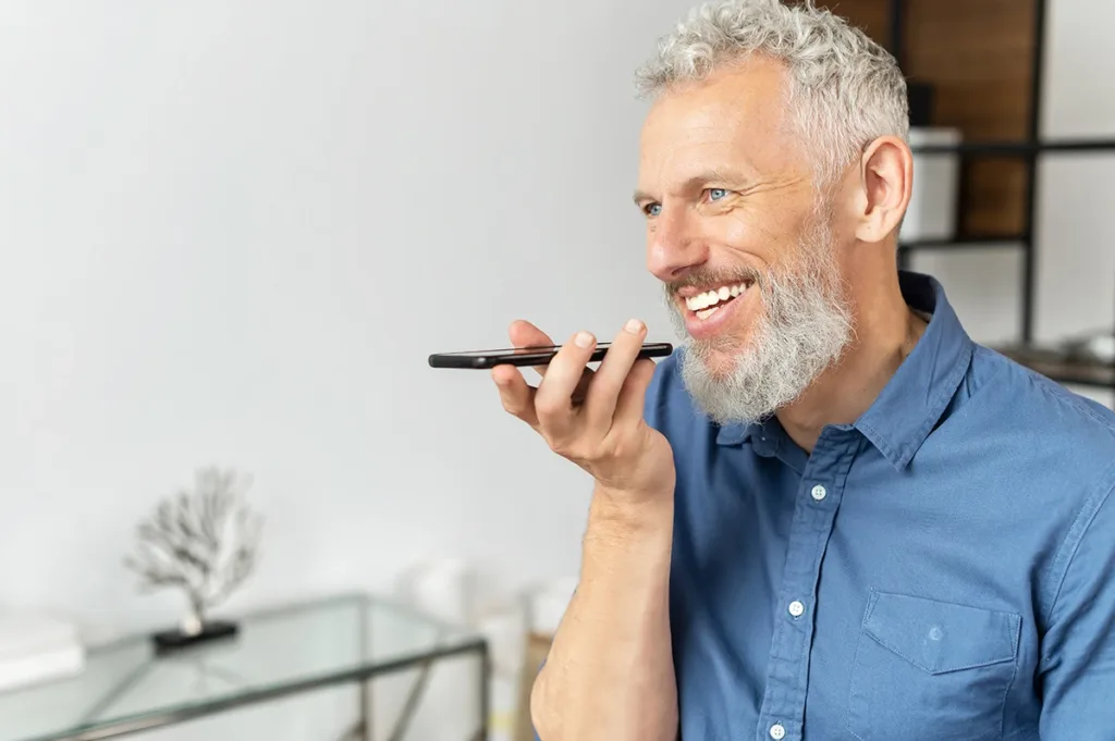 An older man using Siri with hearing aids to have a phone conversation with his iPhone