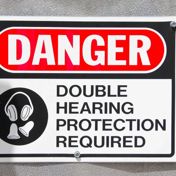 An official-looking sign hanging on a wall that reads, "Danger. Double Hearing Protection Required" in all capital letters.