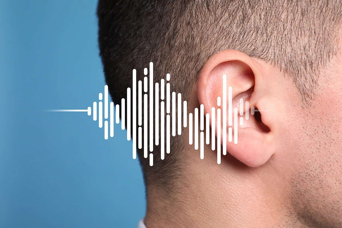 Noise-induced hearing loss concept. Side profile of an ear with sound waves illustration on light blue background.