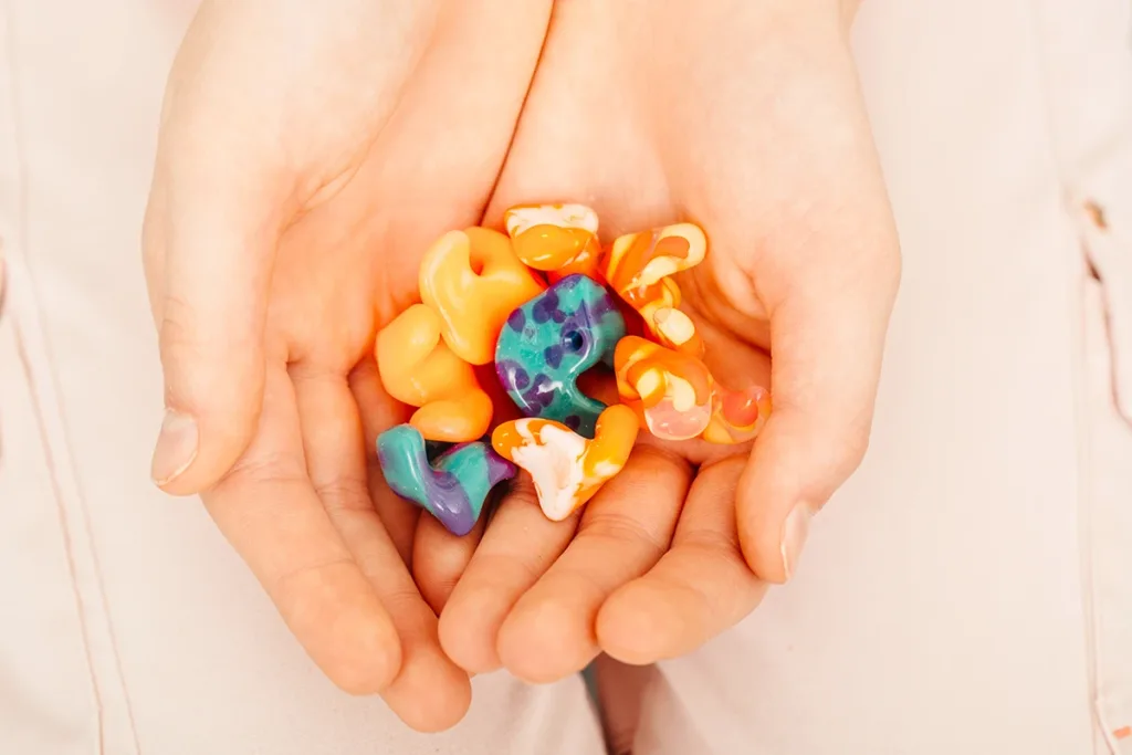 Top view of hands holding multiple unique styles and colors of custom ear plugs which have an incredibly long lifespan of 5 years or more with proper care.