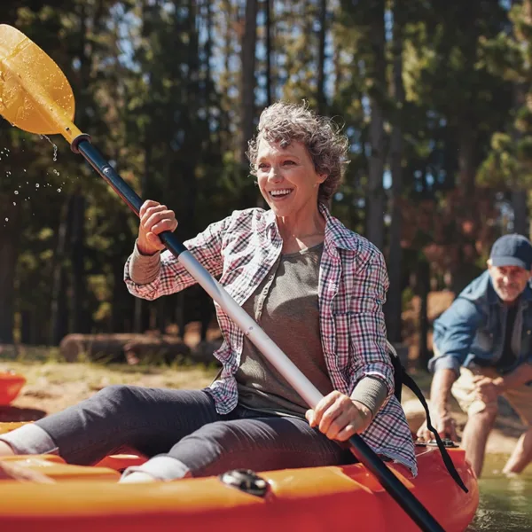 Senior women enjoying a day at the lake kayaking, symbolizing the peace of mind that comes with wearing waterproof hearing aids.