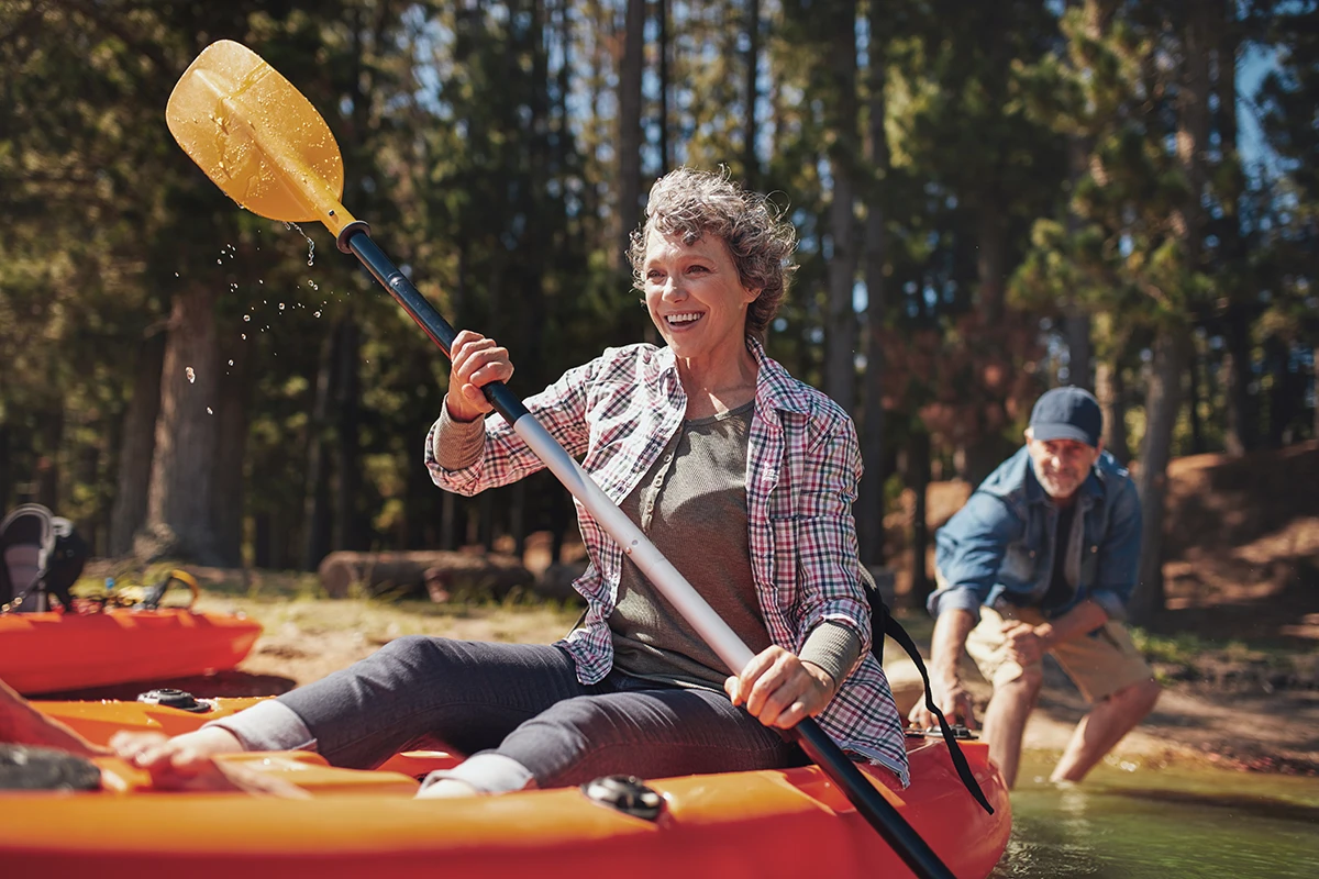 Senior women enjoying a day at the lake kayaking, symbolizing the peace of mind that comes with wearing waterproof hearing aids.