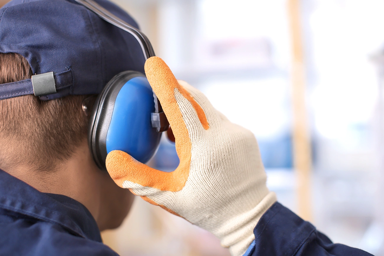 Male worker wearing hearing protector devices earmuffs with a noise reduction rating NRR indoors